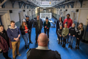 A group of families listen to their prison guard during their Guided Tour of Shrewsbury Prison