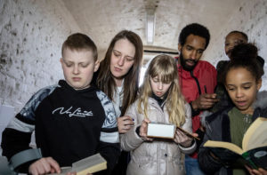 A family in a prison cell reading books and solving clues